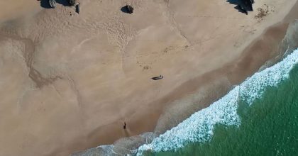 Day tours dingle Aerial view of a sandy beach along the Slea Head drive tour from Dingle, with gentle waves.