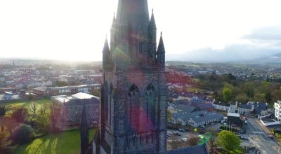 A tall stone church tower rises above a small town on the scenic Slea Head drive tour from Dingle.