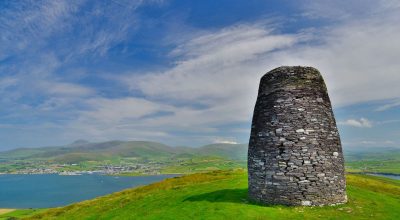 Stone tower on grassy hill overlooks bay—perfect stop on a Dingle Peninsula private day tour.