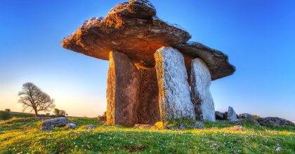 Ancient dolmen on grassy field at sunrise, seen on a Slea Head drive tour from Dingle.
