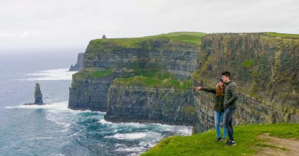 Two people stand on a grassy cliff edge during a Dingle Peninsula private day tour.