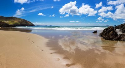 Sandy beach with footprints, rocks, and clouds—perfect for a Dingle private chauffeur tour.